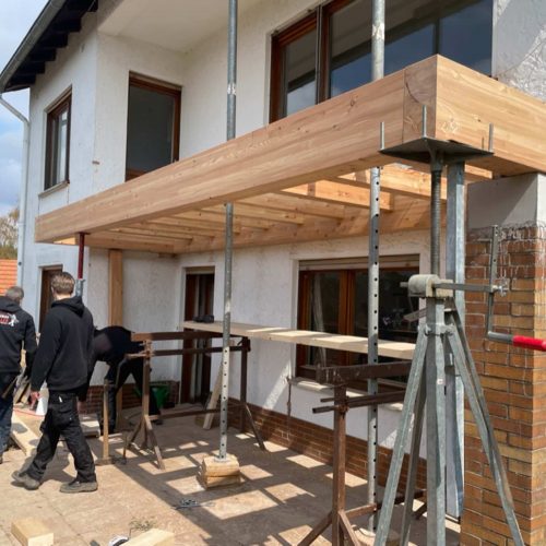 Ferienhaus Kellerwald Handwerker montieren ein Holzvordach an einem Wohnhaus Ferienhaus Edersee