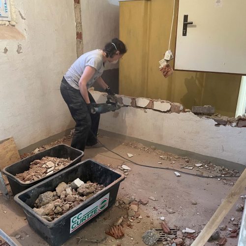 Ferienhaus Kellerwald Person beim Abriss einer Wand in einem Raum mit Baumulden Ferienhaus Edersee