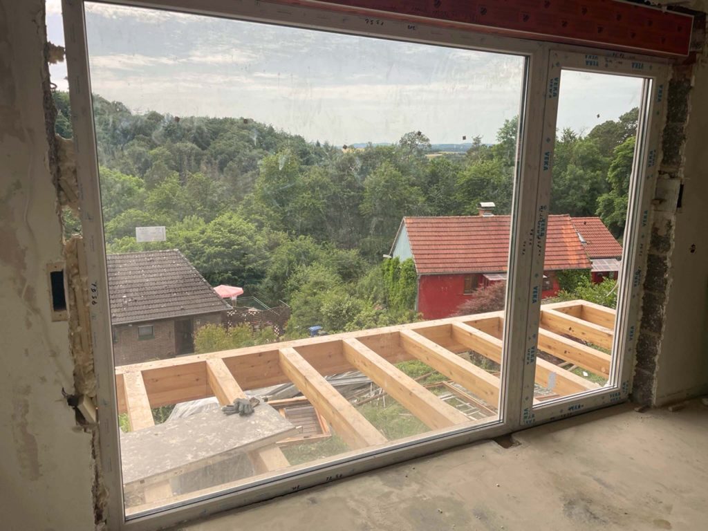 Ferienhaus Kellerwald Blick aus einem offenen Fenster auf eine grüne Landschaft und umliegende Häuser Ferienhaus Edersee
