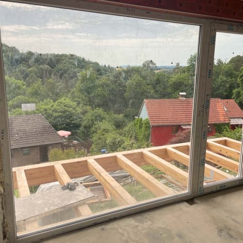 Ferienhaus Kellerwald Blick aus einem offenen Fenster auf eine grüne Landschaft und umliegende Häuser Ferienhaus Edersee