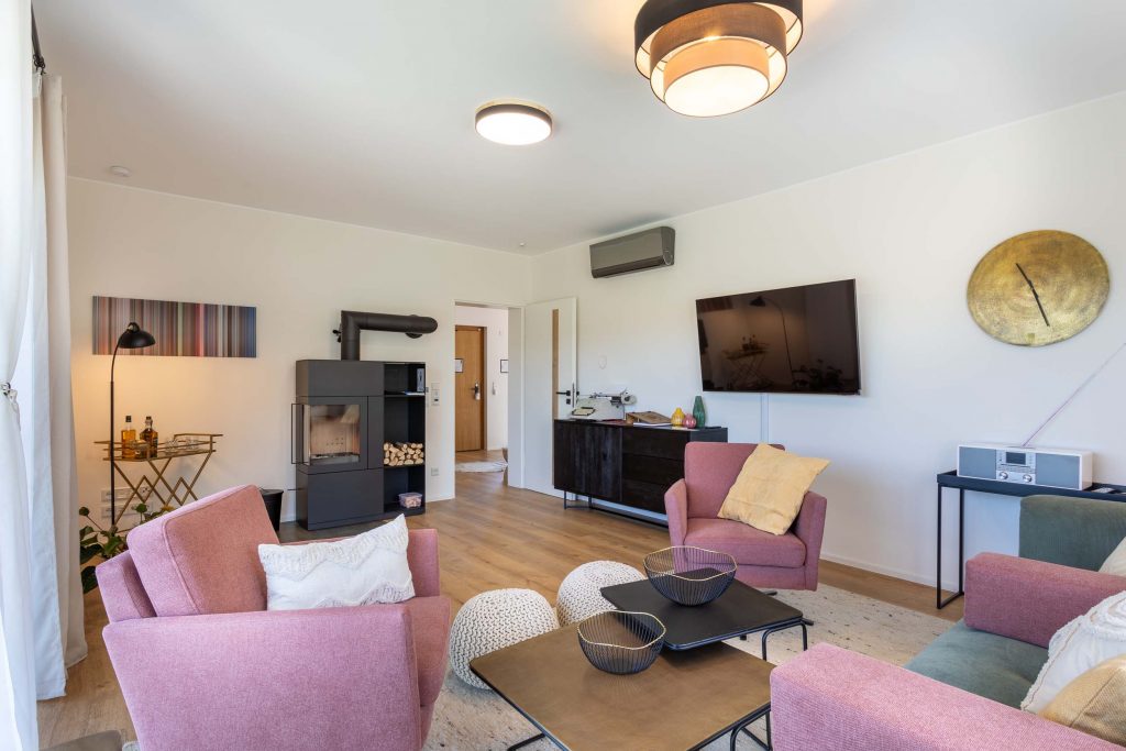 Ferienhaus Kellerwald Heller Wohnraum mit modernen Möbeln, einem Fernseher und einem Kamin Ferienhaus Edersee