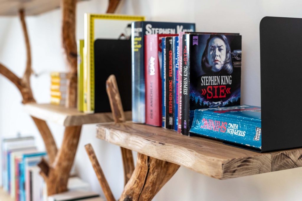 Ferienhaus Kellerwald Regal mit Büchern, darunter Werke von Stephen King und moderne Holzregalgestaltung Ferienhaus Edersee