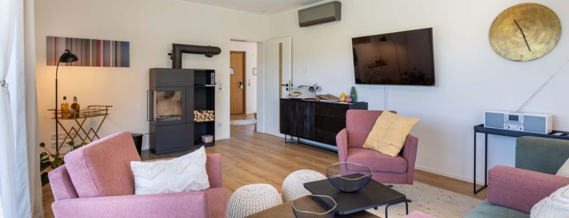 Modernes Wohnzimmer mit Ofen, Fernseher und rosa Sesseln , Ferienhaus Edersee, Ferienhaus Kellerwald