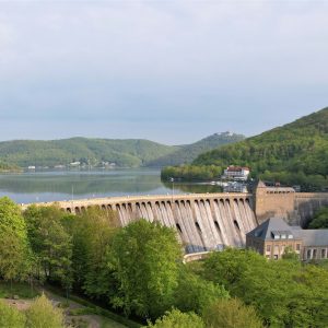 Ferienhaus Kellerwald Staumauer mit grüner Umgebung und Wasser im Hintergrund Ferienhaus Edersee, Partnerschaft mit edersee.com