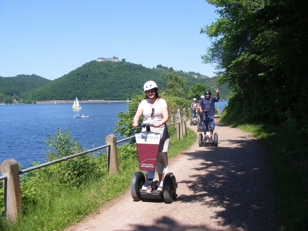 Personen fahren Segways an einem See entlang mit Hügeln im Hintergrund , Ferienhaus Edersee, Ferienhaus Kellerwald
