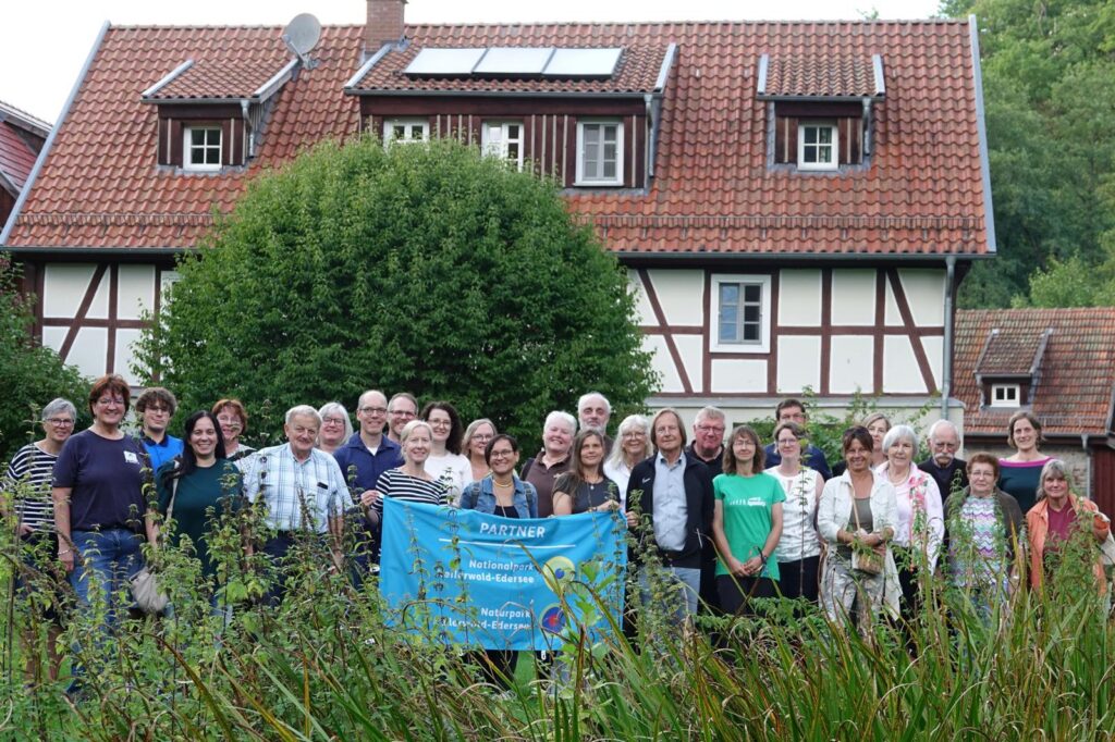 Eine Gruppe von Partner des Nationalpark Kellerwald-Edersee und des Naturpark-Edersee mit einem Banner im Vordergrund der auf die Partnerschaft hinweist.