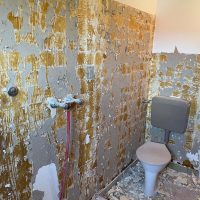 Ferienhaus Kellerwald Renovierungsbedürftiges Badezimmer mit abblätterndem Putz und Toiletteninstallation Ferienhaus Edersee