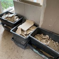 Ferienhaus Kellerwald Bauabfälle in schwarzen Behältern während Renovierungsarbeiten in einem Raum Ferienhaus Edersee, Der Abriss geht weiter