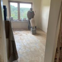 Ferienhaus Kellerwald Ein Handwerker bereitet den Boden in einem renovierten Raum vor Ferienhaus Edersee, Der Abriss geht weiter