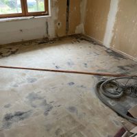 Ferienhaus Kellerwald Unfertiger Raum mit einem alten Bodenbelag und Baumaschinen im Hintergrund Ferienhaus Edersee