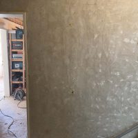 Ferienhaus Kellerwald Unbearbeitete Wand in einem Innenraum mit sichtbarem Putz und Bauwerkzeugen Ferienhaus Edersee