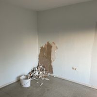 Ferienhaus Kellerwald Ein unvollendeter Raum mit abblätterndem Putz und einem Eimer voller Bauschutt Ferienhaus Edersee